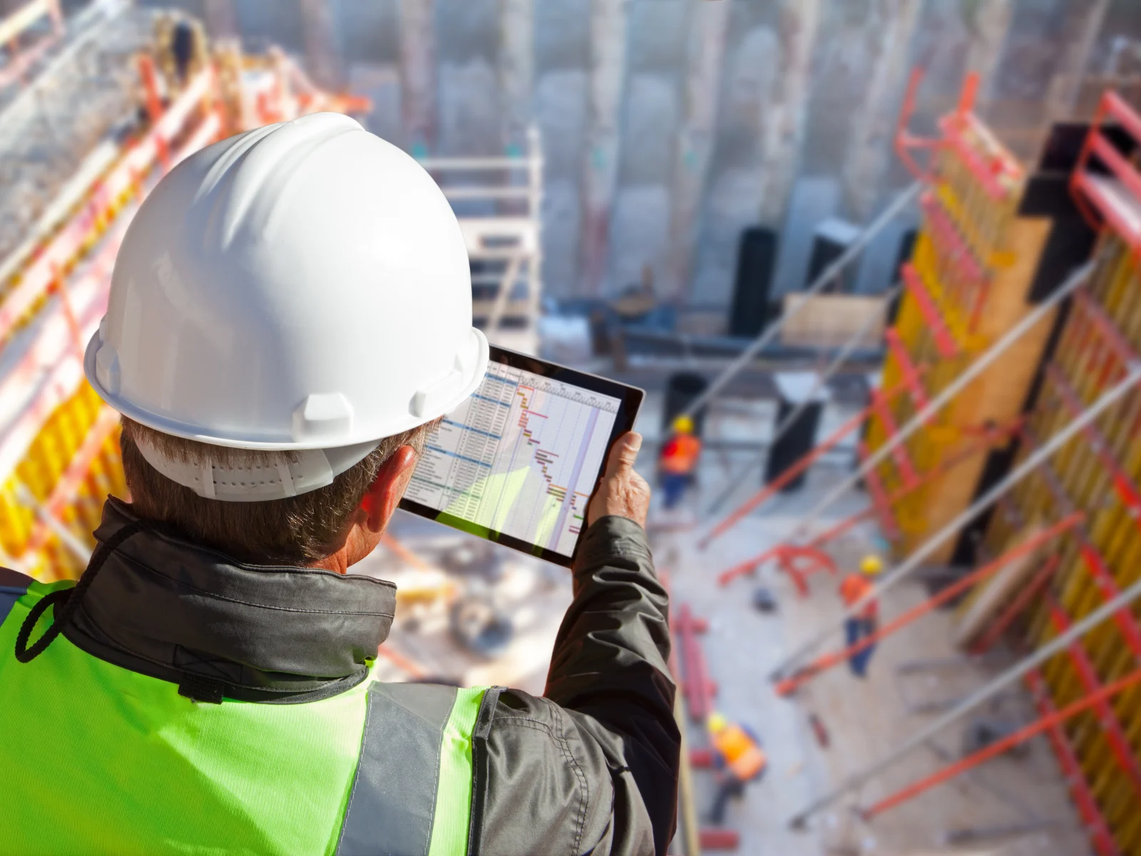 A site supervisor in hi-vis using a rugged tablet on a construction site