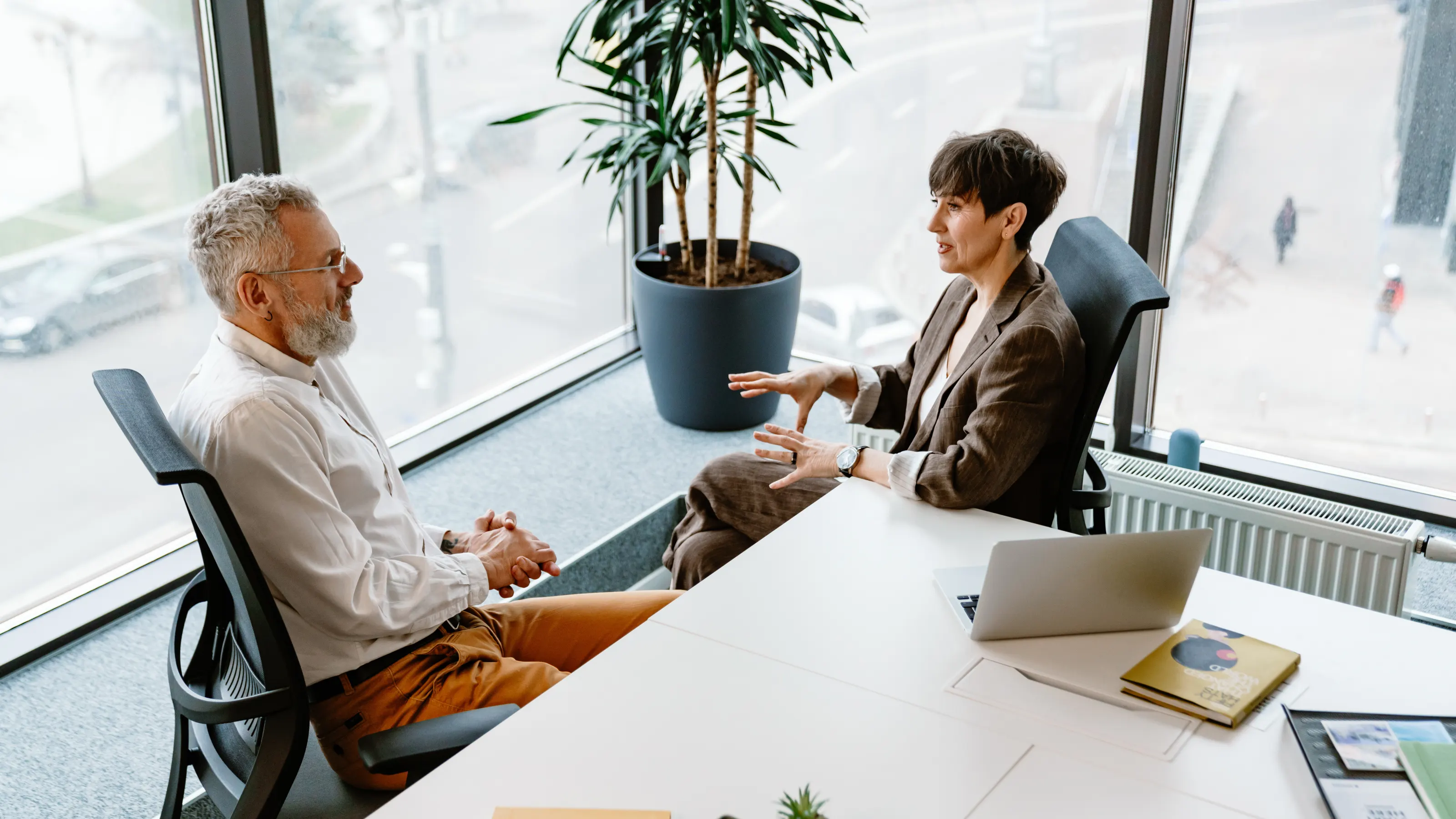 Two people comparing proposals across a meeting-room table