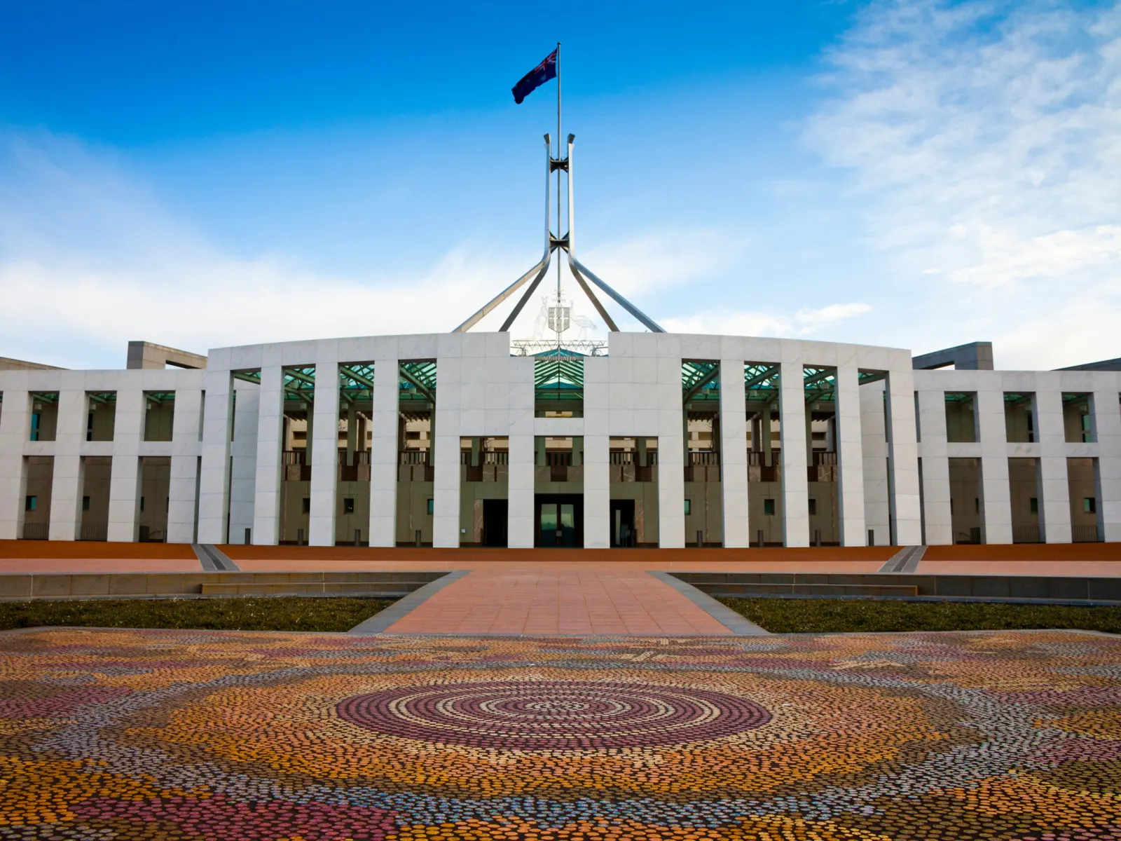Parliament House, Canberra, with the flag flying against a clear sky